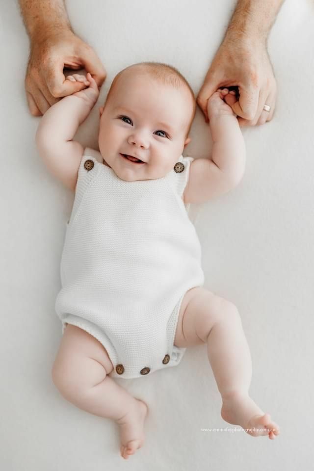 Cheerful Baby in Knitted Romper with Adult Hands